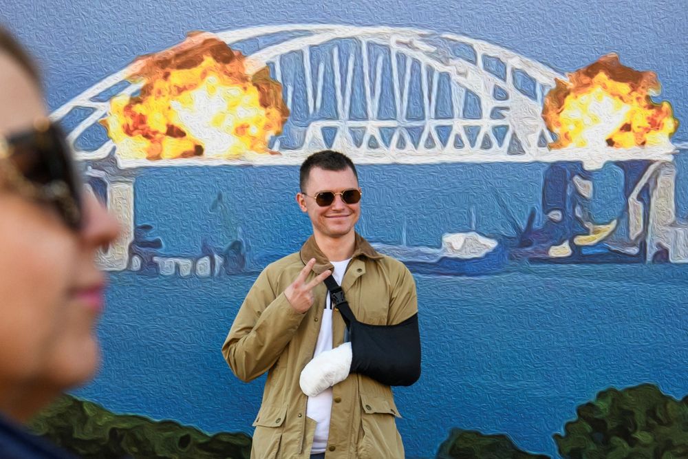 一名手臂受傷的男子，開心跟看板合照。路透社