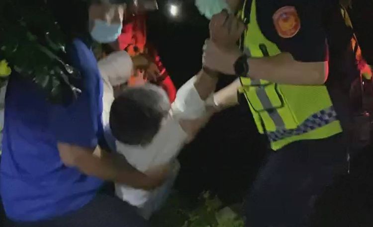 眾人合力將鄒姓男子抬上救護車，緊急送醫救治。民眾提供