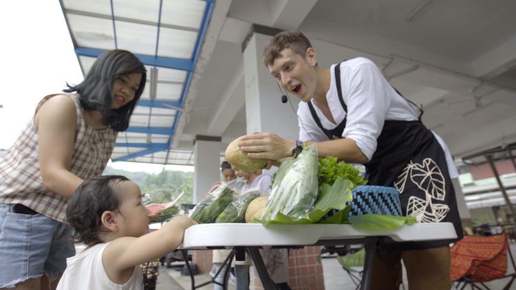 賈斯汀（右）化身叫賣哥，擺攤賣菜爆人氣。沃土影像提供