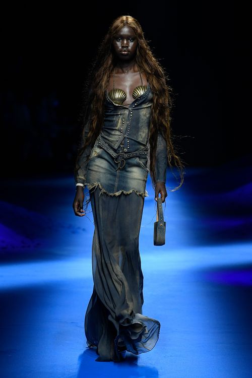 拋光貝殼製成的仿舊金屬感抹胸上衣，搭配有著魚尾般輪廓的丹寧套裝，延續了美人魚的誘惑形象。品牌提供