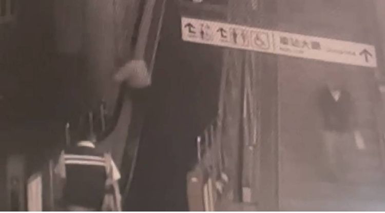 老翁因不想上樓竟抓手扶梯旁欄桿，致身體傾斜，在原地掙扎。讀者提供
