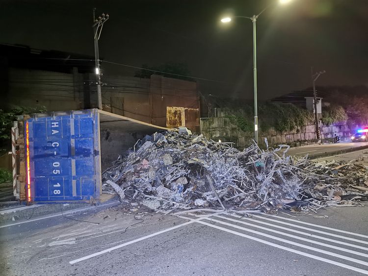 曳引車行駛中爆胎翻覆，廢鐵灑滿整個馬路。陸運鋒攝