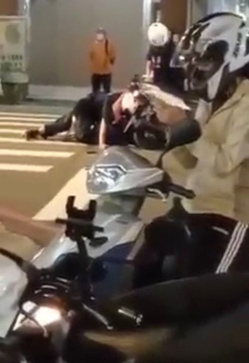 警員壓制彭男時，路旁的女騎士渾然不知，還在滑手機。翻攝臉書爆料公社