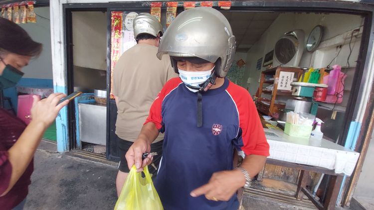 消費者提著整袋肉圓和苗栗熱狗，回家跟家人享用。楊永盛攝