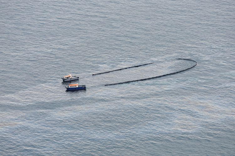 兩艘救援船隻操作攔油索圍堵漏油。路透