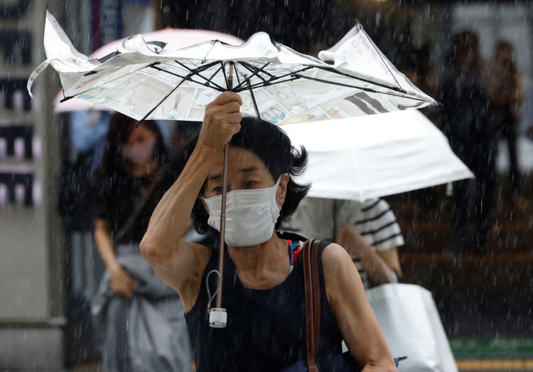 20日東京一名婦女在颱風天撐傘，傘面被颱風吹到開花。路透