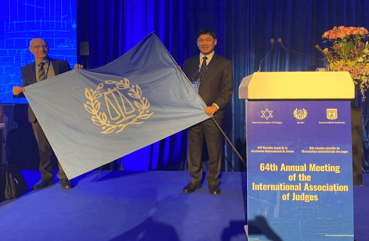 黃瑞明大法官(右)接下國際法官協會年會舉辦會旗。中華民國法官協會提供