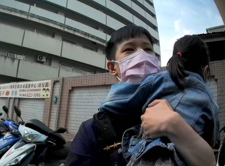 警員黃吉君暖心抱起女童在附近找尋家屬。讀者提供