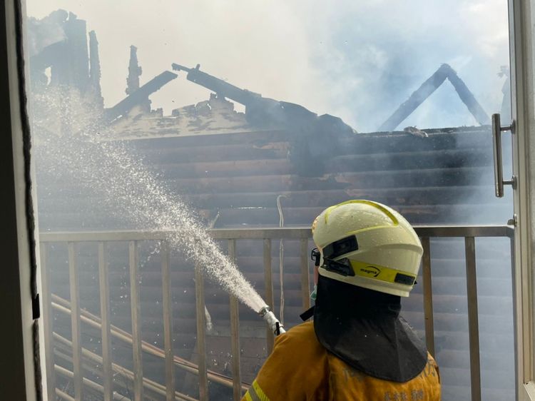 消防人員拉水線射水滅火。讀者提供