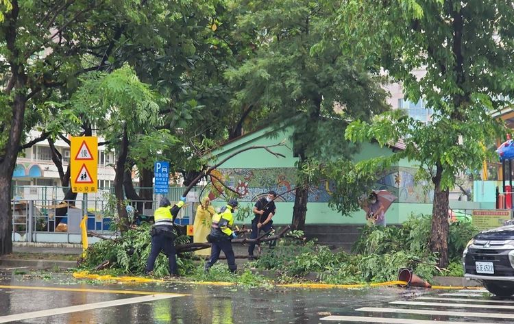 3名警員及熱心民眾合力將倒塌的路樹移往路旁。讀者提供