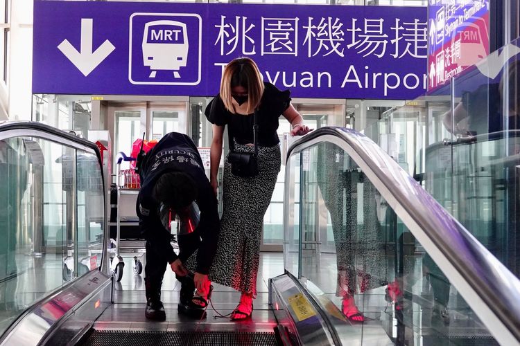 機場保全人員發現異狀，上前協助女子拖下涼鞋。施昂強攝