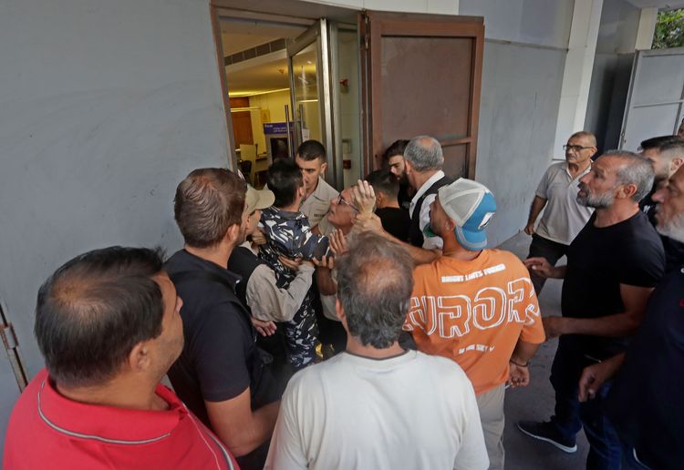 黎巴嫩部分銀行26日恢復營業，許多民眾試圖擠進銀行提款，遭警衛人員攔阻，氣氛緊張。法新社