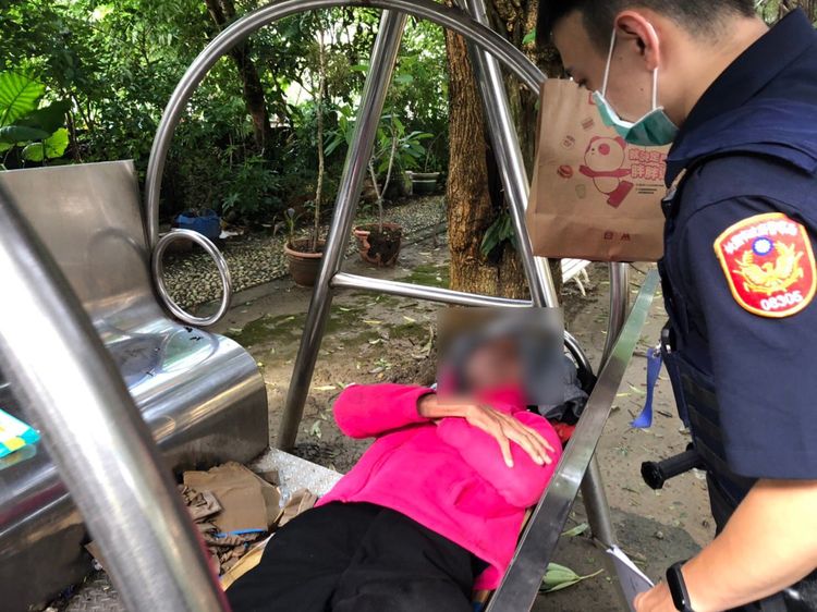 彭姓街友獨自躺在公園鐵椅，警員趨前關心。平鎮警分局提供