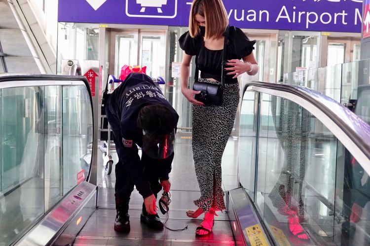 機場保全人員發現異狀，上前協助女子拖下涼鞋。施昂強攝