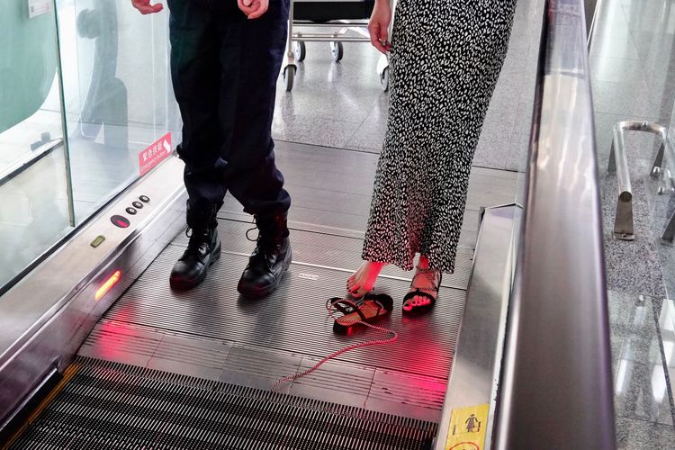 女子涼鞋拖下後，涼鞋綁腿長繩還卡在電扶梯縫隙中。施昂強攝