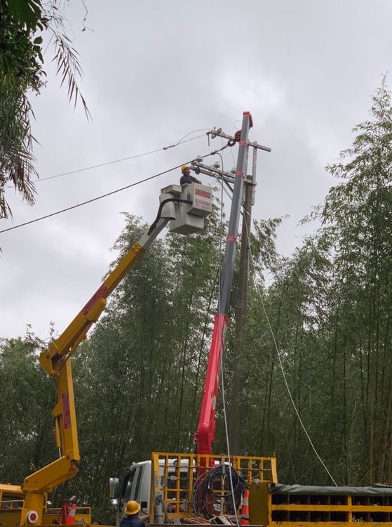 因颱風風雨影響山區土石鬆動，今天竹60線尖石鄉那羅區因樹木倒塌壓倒高壓電桿，台電人員冒雨搶修中。台電提供