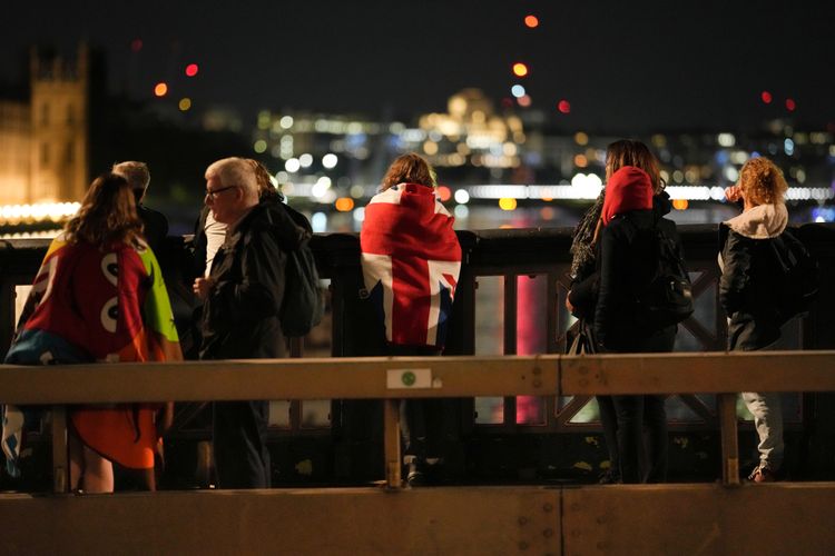 9月的倫敦晚上氣溫不到10度，但卻阻擋不了民眾排隊的意願，還有民眾披著英國國旗。美聯社