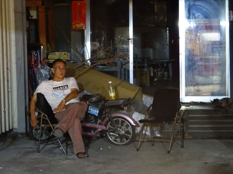 王先生坐在自家門口，無奈地發呆。江孟謙攝