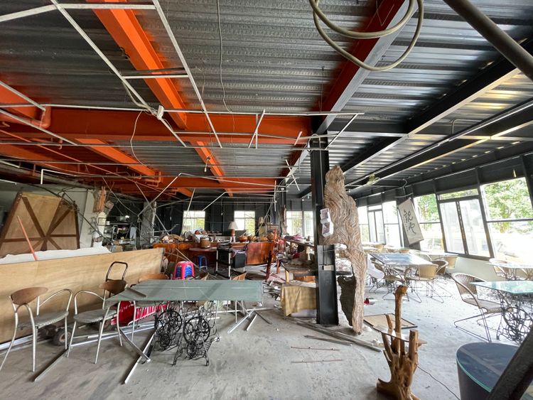 茶莊內木製桌椅斷裂散落，地上還有無數摔破的餐盤，牆壁磁磚也零散的堆疊在走道，頭頂還有裸露的電線，行走時必須抬頭看望天花板，稍有不慎可能碰撞到橫亙的梁柱。彭欣偉攝