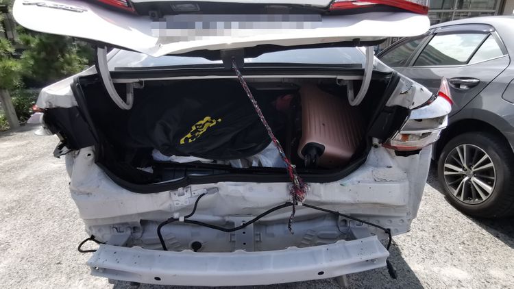 整台轎車尾部車禍受損嚴重，行李箱內擺滿行李，但有一堆「小強」到處爬。林泊志攝