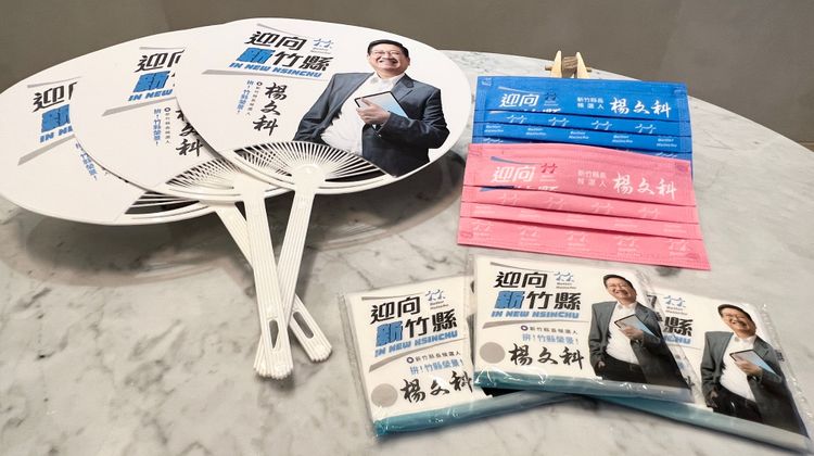 競選小物方面，以「竹」字樣LOGO設計出藍色與粉紅色兩種跳色造型口罩，以及消暑荷葉扇與面紙。楊文科競選總部提供