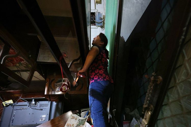 陳小姐艱難地穿過傾斜的櫃子去開燈。林林攝