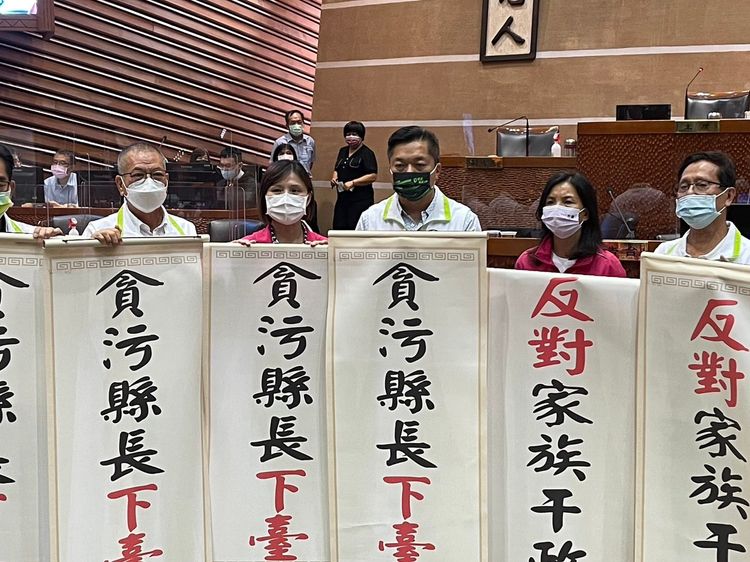 民進黨宜蘭縣議會黨團趁林姿妙在議會上台致詞時突襲，高舉「貪污縣長下臺」、「反對家族干政」捲軸。民進黨宜蘭縣黨部提供