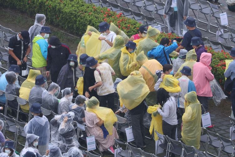 在國慶大會開始前忽然下起雨，前來觀禮的民眾急忙穿上雨衣。彭欣偉攝