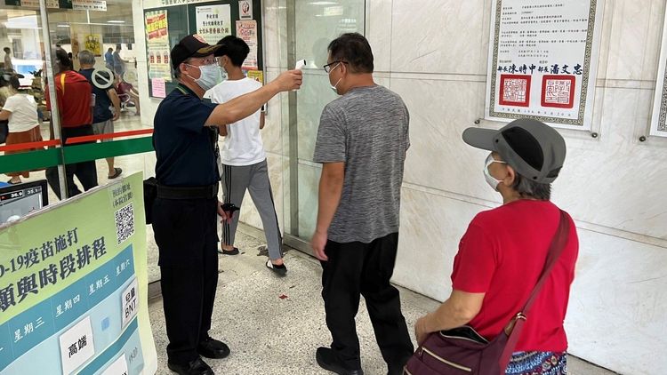 醫院保全員在入口處幫民眾量體溫。圖非當事保全。魏嘉良攝