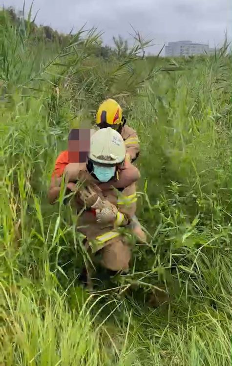 消防人員背著黃男走出草迷宮。警方提供