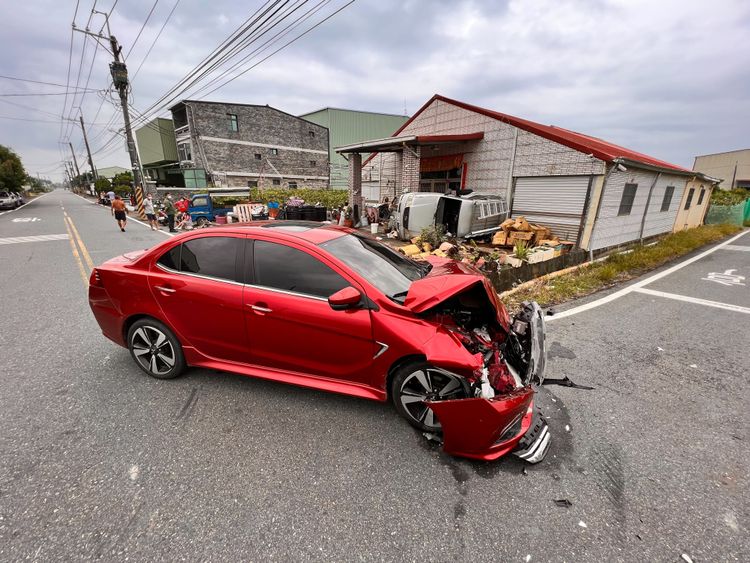 紅色汽車的車頭嚴重毀損、零件四散。侯昌騰攝