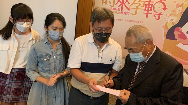 爸爸帶著試管雙胞胎姊妹請不孕症權威醫師李茂盛在其著作上簽名。曾雪蒨攝