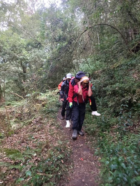 搜救人員揹負著婦人下山，行走約1小時。民眾提供
