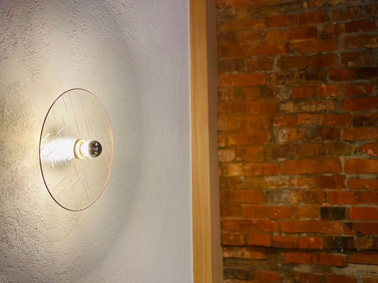 壁面上裝設以台灣古花紋窗玻璃手工訂製的燈具，十字星、海棠紋、牡丹紋優雅地透過暖黃色燈光與磚牆遙相輝映。曾仲葳攝