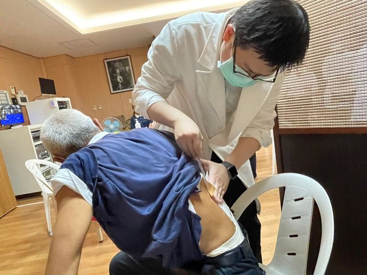 志工筋骨痠痛，中醫師治療後貼上藥布。慈濟提供