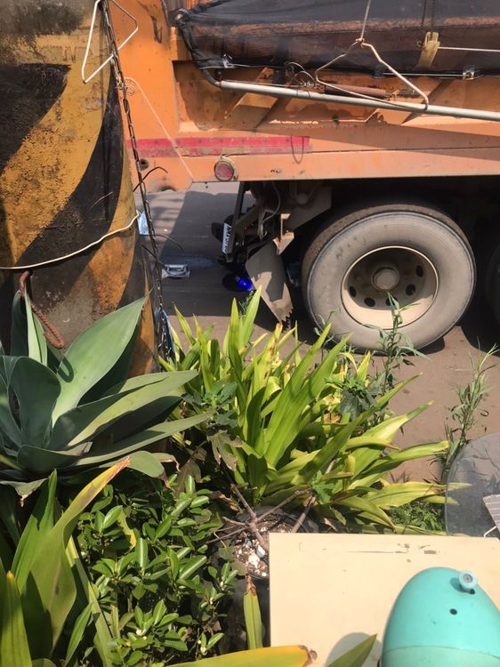 汪姓男子駕駛砂石車，倒車時未注意正後方的警用機車，撞倒後卡在車底。讀者提供