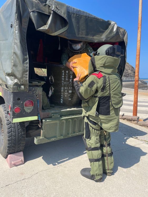 防爆毯包裹的未爆彈放入防爆桶攜回處理。軍方提供