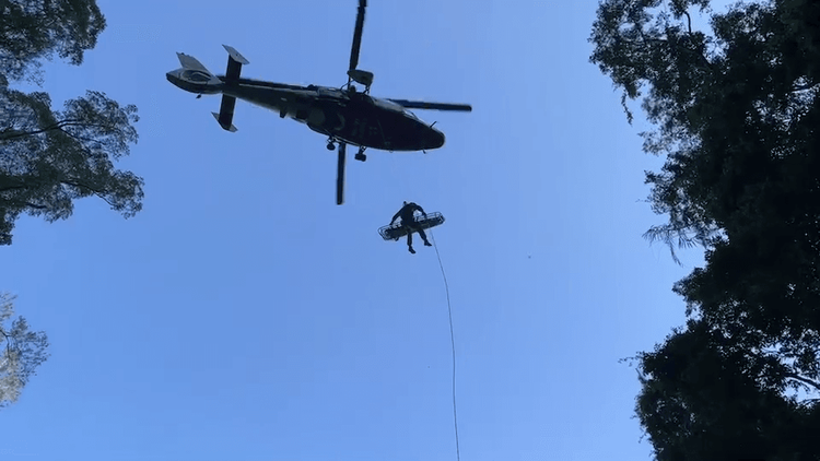 直升機冒險在山谷吊掛，擔架在山谷中旋轉上下救人。民眾提供