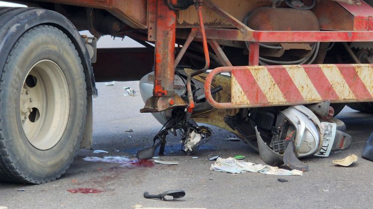 機車卡在拖車輪下支離破碎，一旁血跡更是觸目驚心。許逸民攝